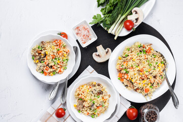 Couscous is a dish made from wheat grains (semolina) or millet. Lean couscous with mushrooms, corn, peas, herbs, tomatoes. Top view. Flatlay. Couscous on a light background.