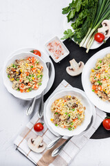 Couscous is a dish made from wheat grains (semolina) or millet. Lean couscous with mushrooms, corn, peas, herbs, tomatoes. Top view. Flatlay. Couscous on a light background.