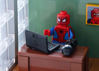 Fototapeta premium Tambov, Russian Federation - February 12, 2025 Lego Spider-Man minifigure working behind a laptop on his workplace at the office