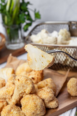 Cauliflower fries cut into slices on a fork, lean dish, cauliflower in batter. Healthy fast food. Low-calorie food fries. Cabbage, tomatoes. Deep fryer. High quality photo.