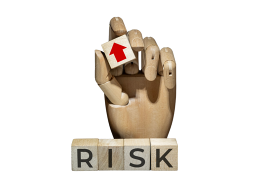 sztuczna ręka trzymająca kostkę z czerwoną strzałką w górę nad napisem na kostkach: RISK. Koncepcja zarządzania ryzykiem.