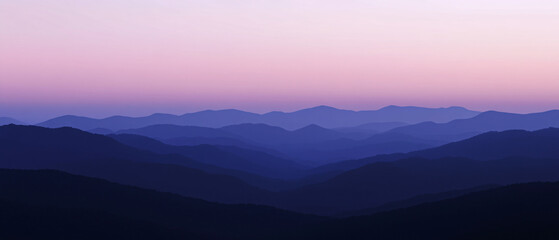 Fototapeta premium A breathtaking landscape of layered mountain ridges at dawn with a gradient sky shifting from pink to blue creating a serene atmosphere