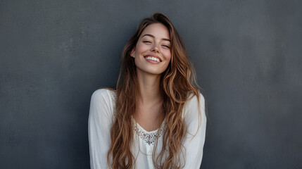 Obraz premium A cheerful young businesswoman poses confidently against a gray wall, radiating happiness and professionalism