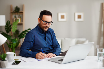 Obraz premium Focused entrepreneur working remotely from home office taking notes