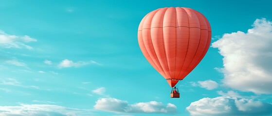Obraz premium A vibrant hot air balloon soars against a clear blue sky, surrounded by fluffy clouds, creating a serene and adventurous scene.