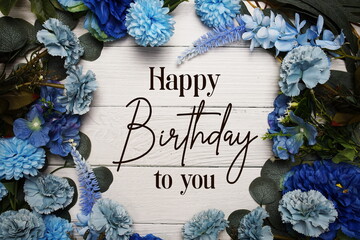 Happy Birthday to you text with blue flowers bouquet decoration on wooden background