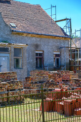 Restoration of an old farmhouse. In the garden are new roof tiles for the repair of the roof and the old bricks of the facade.