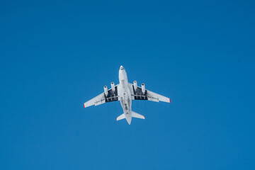 An Airplane in Flight Above a Clear Blue Sky A Stunning Aerial View of an Aircraft Captured from Below, Showcasing its Elegant Design and Dynamic Movement Through the Air