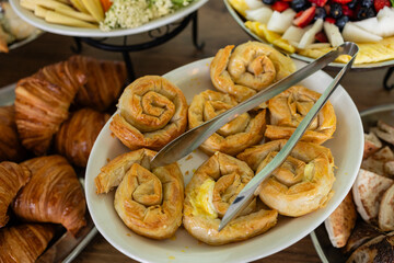 flaky phyllo dough spinach rolls on a white platter at brunch event