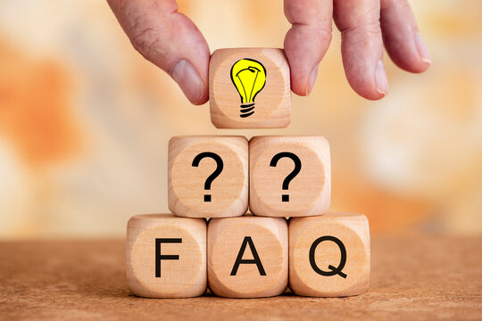 Mehrere Holzw&uuml;rfel bilden eine Pyramide und sind bedruckt mit Fragezeichen und FAQ, dar&uuml;ber eine Hand mit einem Holzw&uuml;rfel bedruckt mit einem Gl&uuml;hbirne als Symbol f&uuml;r Idee oder Geistesblitz