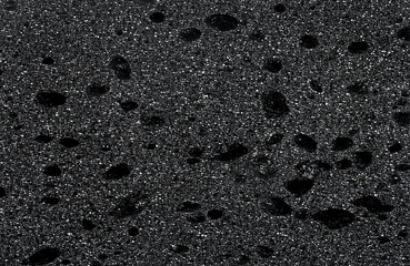 Black foam rubber texture as background, top view. Surface of the sponge. Abstract black porous...
