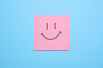 Happy face on square memo paper, blue background. Business concept