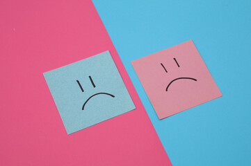 Unhappy faces on square memo papers, pink blue background. Business concept