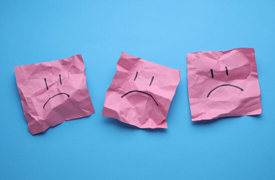 Naklejki Unhappy faces on crumpled square memo papers, blue background. Business concept