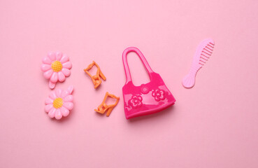 Miniature doll bag with comb and shoes on pink background. Fashion concept