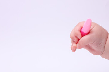 Child's hand holding toy lipstick on a white background