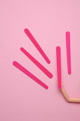 Doll hand holding Nail files on a pink background