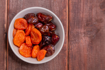 Dried dates and apricots in a bowl on a wooden table iftar suhoor month of ramadan. copy space