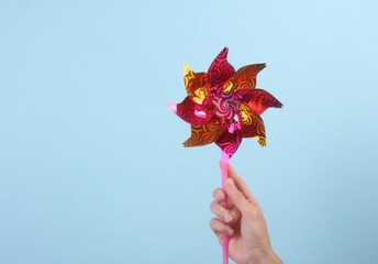Woman's hand holds a children's windmill on a stick