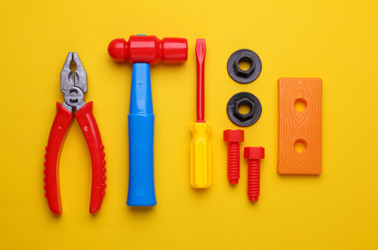 Set of children's toy tools on a yellow background. Flat lay