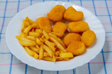 French fries and golden chicken nuggets on a plate close-up.