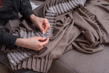 Women's hands in a close angle put hooks on the ribbon on the curtains. Brown curtains.