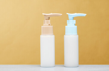 Two bottles of cream dispenser on the table, yellow background