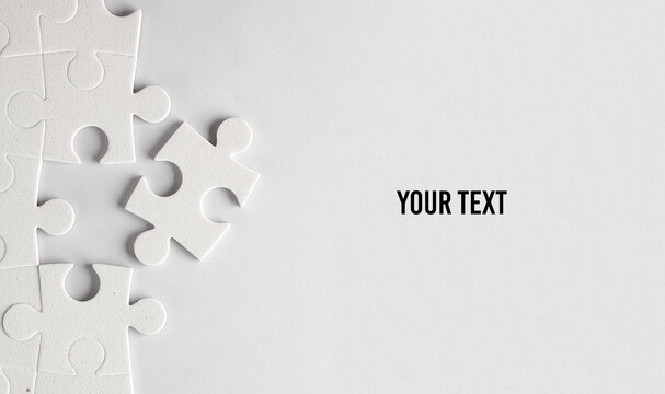 White jigsaw puzzle pieces on a gray background. Your text, copy space for information