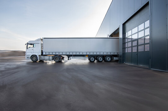 A large white semi truck is parked in front of a building