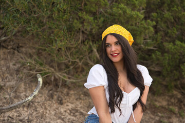 Portrait of a young, pretty woman, with black hair, wearing a white shirt, jeans and a yellow scarf...