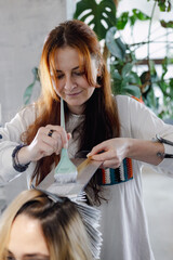 Fototapeta premium A professional hairstylist blow-drying and styling a client’s blonde hair in a modern salon setting.