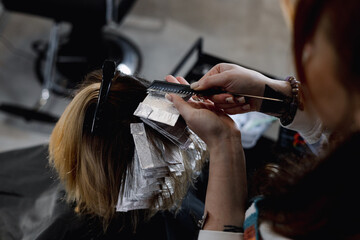 Fototapeta premium A professional hairstylist blow-drying and styling a client’s blonde hair in a modern salon setting.