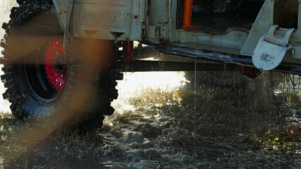 The solid tire of the car with the red rim was partially submerged in the muddy water, droplets...