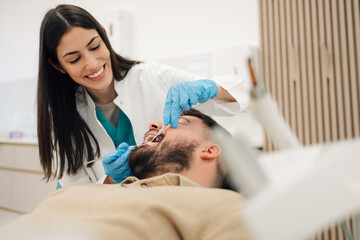 Female dentist examining patient's teeth in modern dental clinic