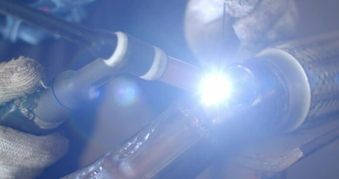 Technician is welding pipe to add position of o2 sensor.Car pipe welding.The hand of a mechanic or welder is fixing a car exhaust system.Tig welding makes the welds come out beautiful.
