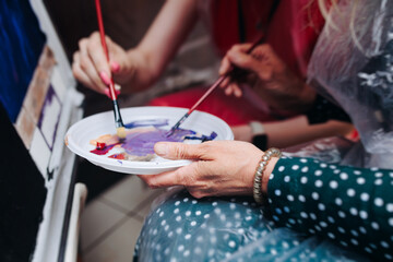 Process of drawing, group class of talented female students with painting easels and canvases during workshop lesson of watercolour painting indoors, drawing class for adult artists in art school