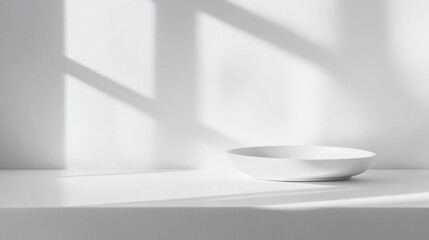 Fototapeta premium Minimalist image of an empty white bowl on a white surface, illuminated by sunlight casting shadows