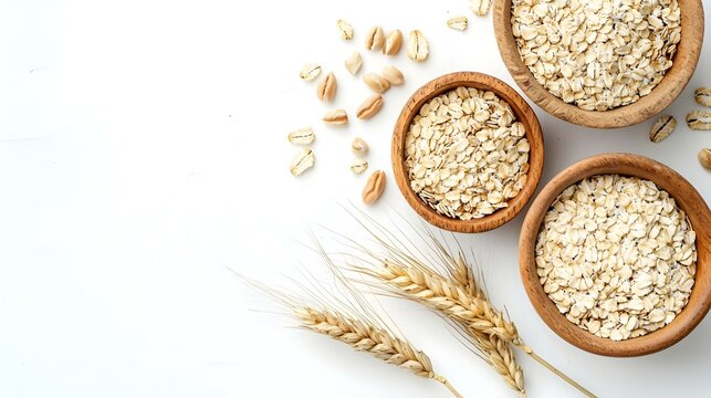 Oatmeal and oat in bowls near sprigs of wheat