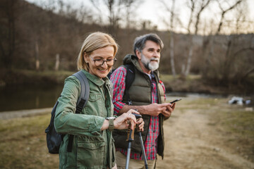 aged couple hiker backpacker explore forest look at smart watch