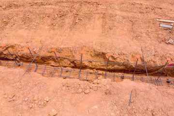 Foundation trench for building is being prepared, showcasing rebar tied together in ground at construction site.