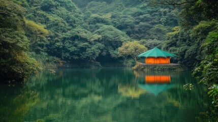 Obraz premium Tranquil orange hut nestled by a serene lake surrounded by lush green forest