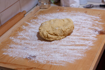 Ball of homemade dough on floured wooden surface
