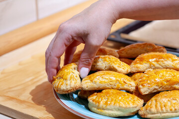 Hand picking a freshly baked pastry from a plate
