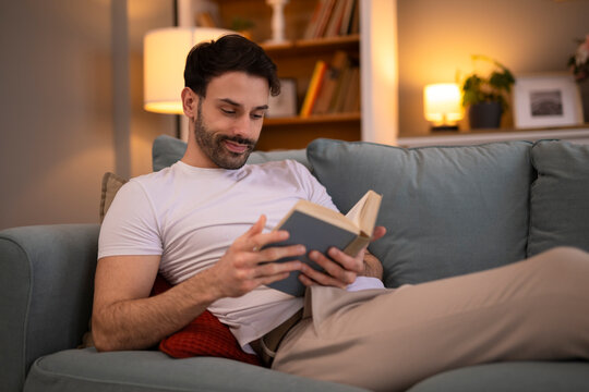 Young studnet reading book at home. Resting on bed and reading a book