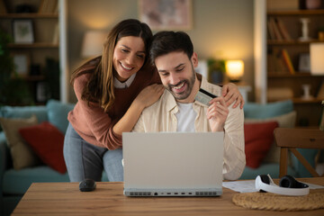 Couple using laptope to buy online. Man holding credit card to pay bills online
