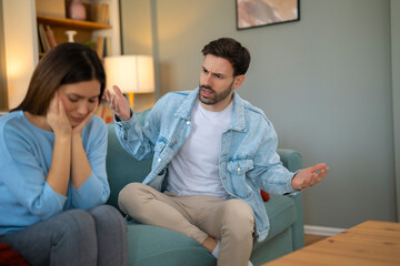 Fototapeta premium Sitting on the Couch at Home, Boyfriend Screams Accusing Girlfriend. Relationship Problems by Reason of Disagreement