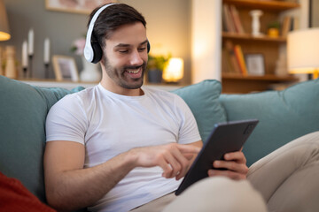Man sitting on sofa and using digital tablet for music