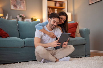 Young couple using digital tablet in living room