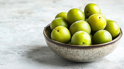 Fresh ripe organic green plums or greengage in bowl on white rustic background, heap of summer fruits concept 