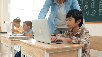 Caucasian teacher helping asian student coding engineering prompt while diverse student using software generated AI. Smart happy attractive children sitting and programing system. Education. Pedagogy.